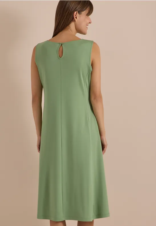 Rückenansicht einer Frau in ärmellosem, knielangem, olivgrünem Kleid mit kleinem Rückenausschnitt.