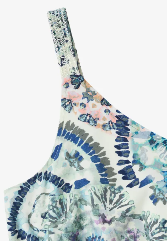 Un haut asymétrique à imprimé floral multicolore dominé par des tons bleus et roses.
