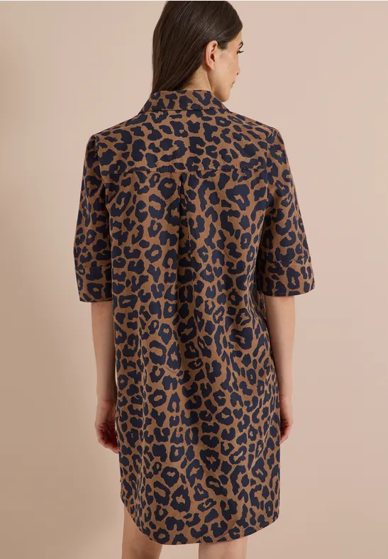 Frau mit schulterlangem Haar trägt Hemdkleid im Leopardenmuster.