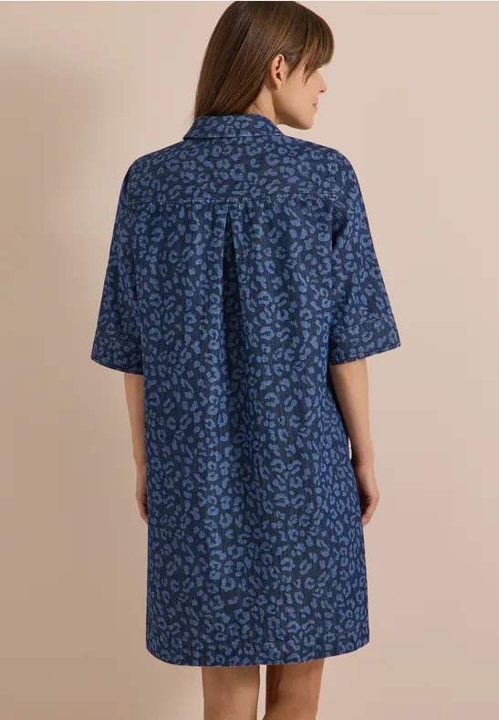 Frau von hinten in lockerem, blauem Hemdkleid mit kurzem Arm und dezentem Muster.