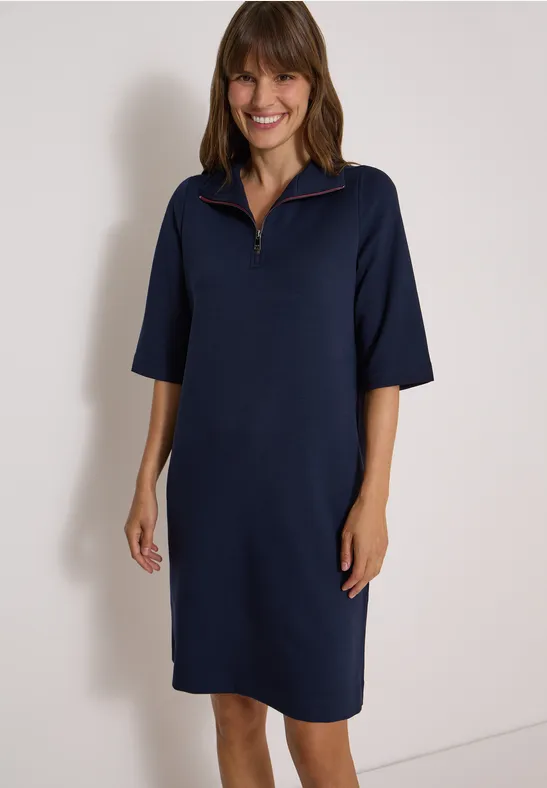 Frau in navyblauem, knielangem Kleid mit halblangen Ärmeln und Reißverschluss