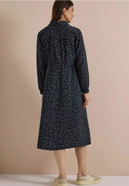 Frau von hinten in dunkelblauem, gemustertem Midi-Kleid mit langen Ärmeln und Kragen.
