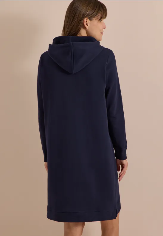 Rückenansicht einer Frau in einem dunkelblauen Kapuzenkleid.