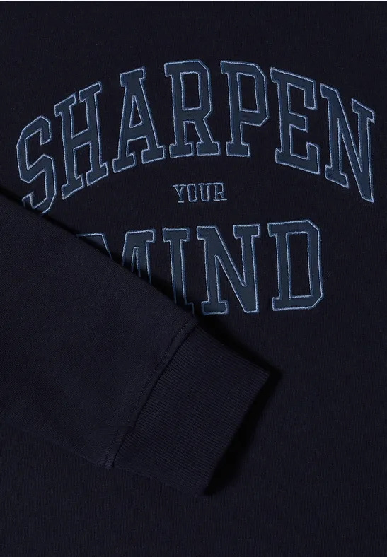Dunkelblauer Pullover mit hellblauem Schriftzug 'SHARPEN YOUR MIND' und einem Ärmel, der das Motiv überdeckt.
