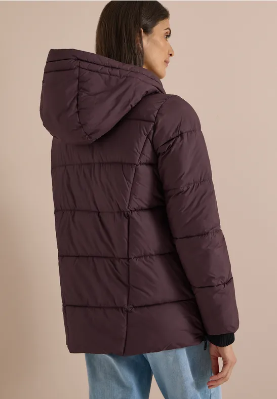 Frau trägt lila gesteppten Winterparka mit Kapuze, Rückansicht.
