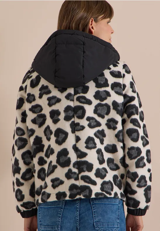 Frau von hinten in Leoprint-Fleecejacke mit schwarzer Kapuze und Jeans.