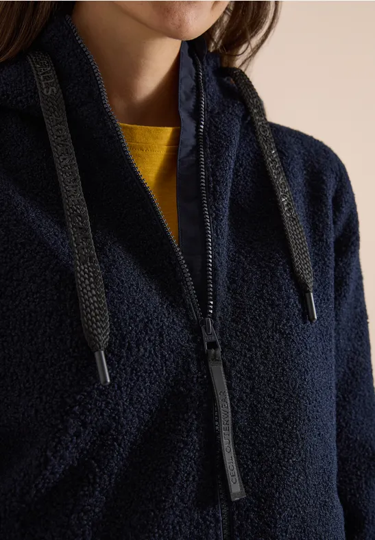 Flauschige dunkelblaue Fleecejacke mit Reißverschluss, Kordelzug und gelbem Shirt darunter.
