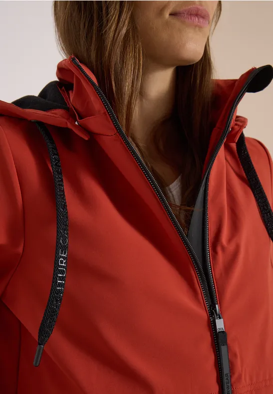 Rote Softshell-Jacke mit Reißverschluss und schwarzem Kordelzug.