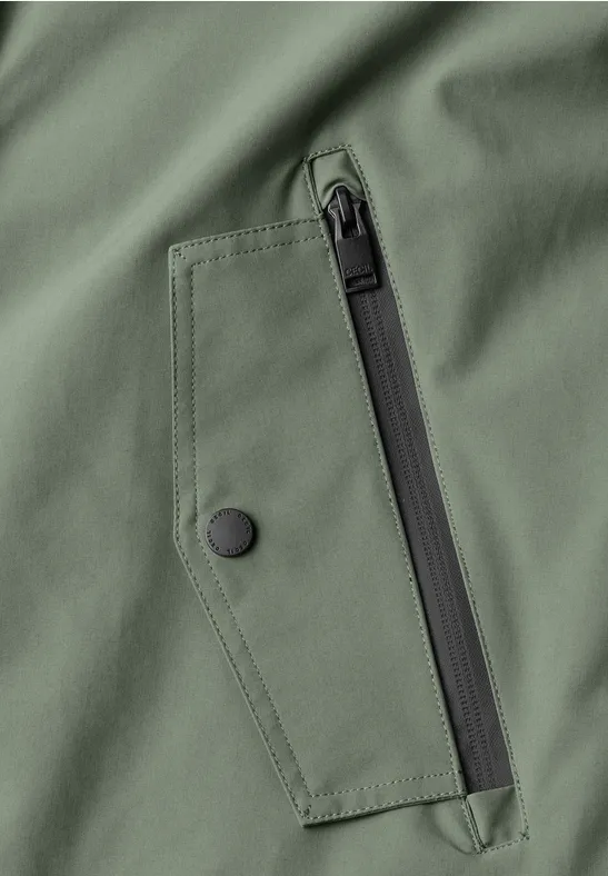 Nahaufnahme einer olivgrünen Jacke mit Reißverschluss- und Druckknopf-Tasche