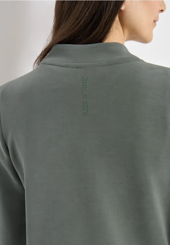 Rückansicht einer Person in einem graugrünen Poloshirt.