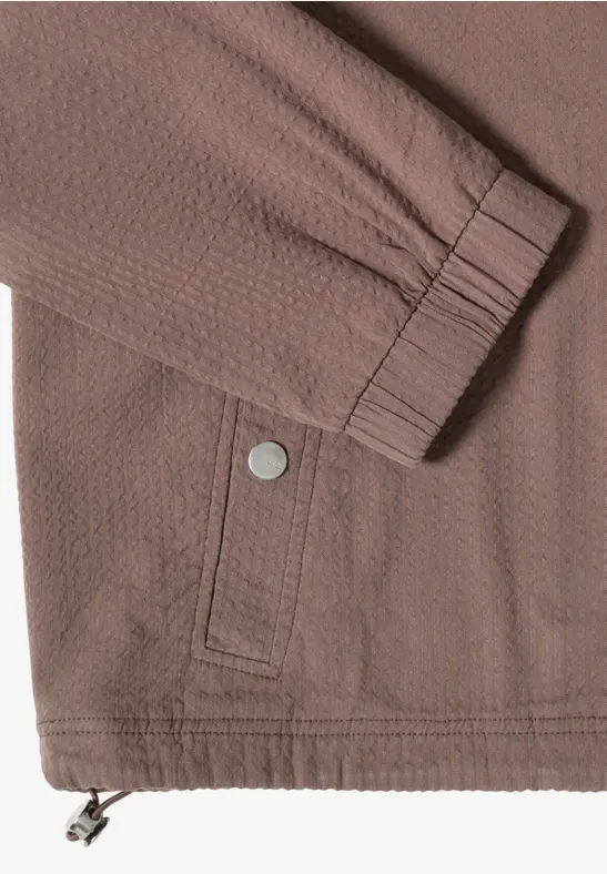 Bruine gestructureerde jas met elastische mouwboord, opgestikte zak, drukknop en koordsluiting onderaan