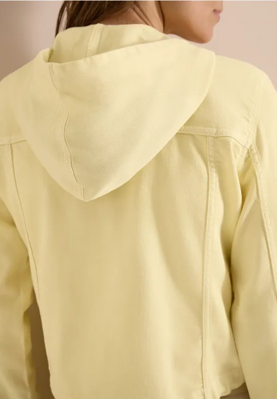 Rückenansicht einer Person in einer hellgelben Kapuzenjacke.