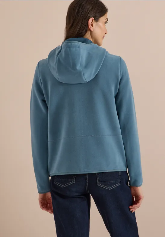 Vrouw van achteren in een blauwe capuchontrui en spijkerbroek