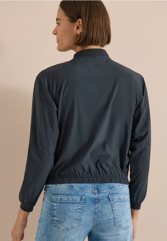 Personne de dos portant une veste sombre et un jean bleu.