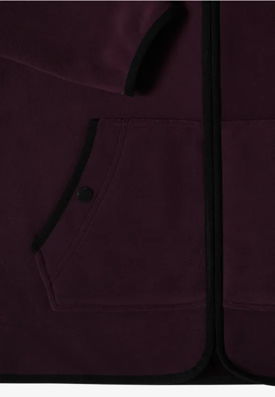Close-up van een bordeaux fleecevest met rits en voorknopzak.