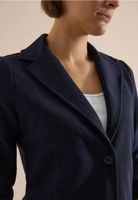 Plan mi-portrait d’une femme en veste bleu foncé et top blanc