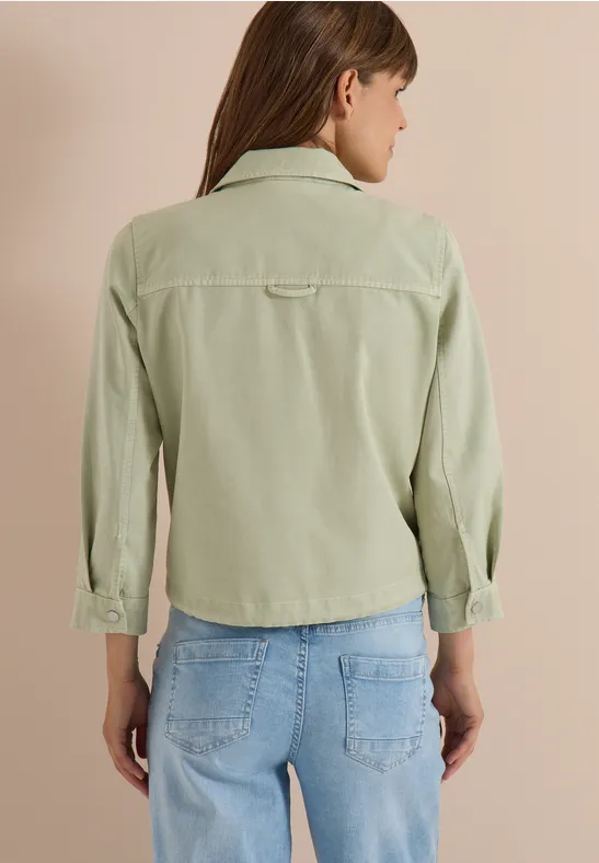 Frau von hinten in hellgrüner Cordjacke und blauen Jeans.