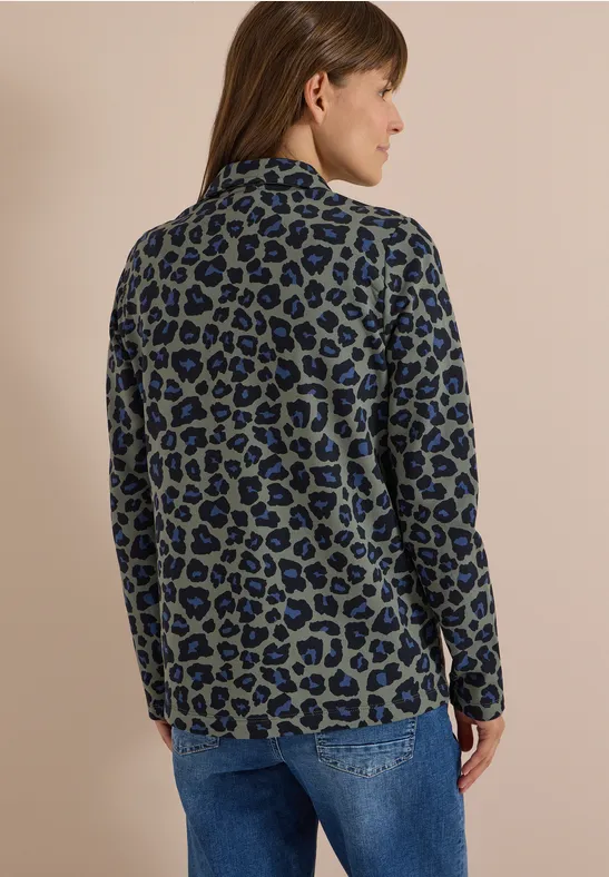 Vue de dos d'une femme en blazer léopard bleu-vert et jean.