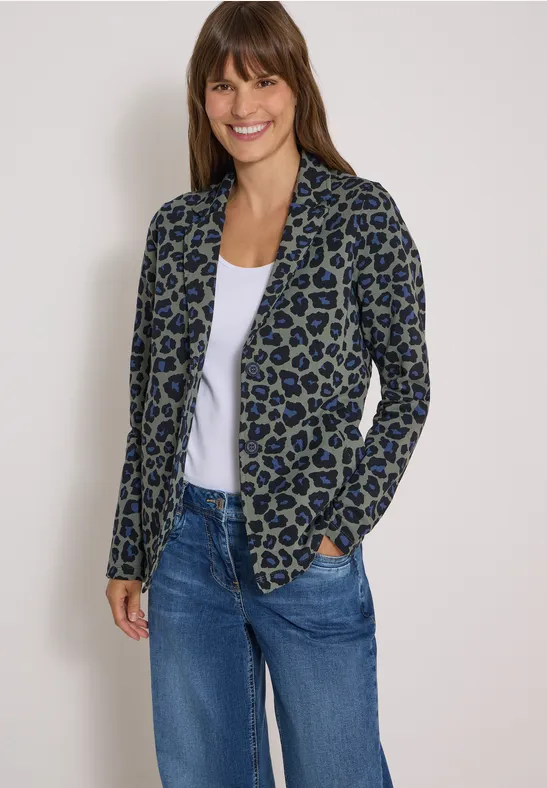 Femme souriante en blazer léopard décontracté, t-shirt blanc et jean.