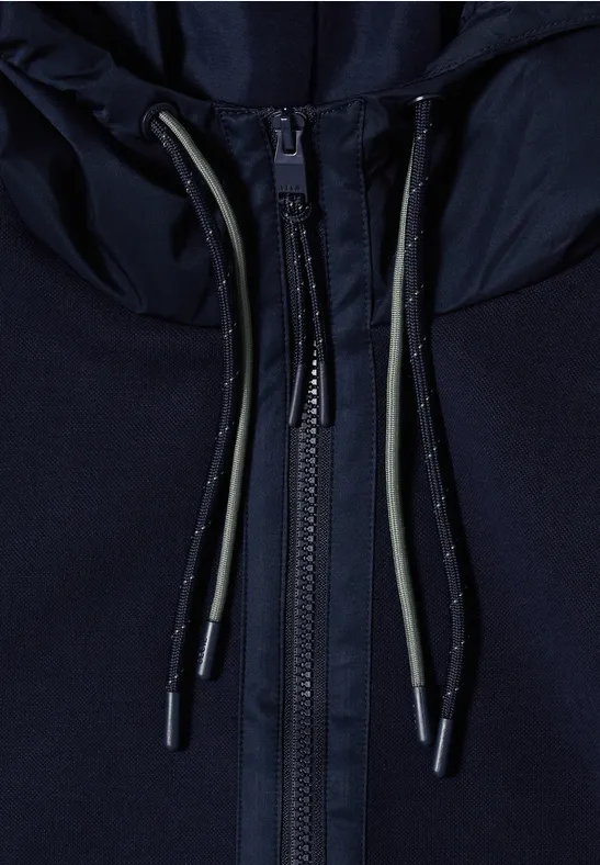 Close-up van een donkerblauwe rits met koordjes en metalen uiteinden.