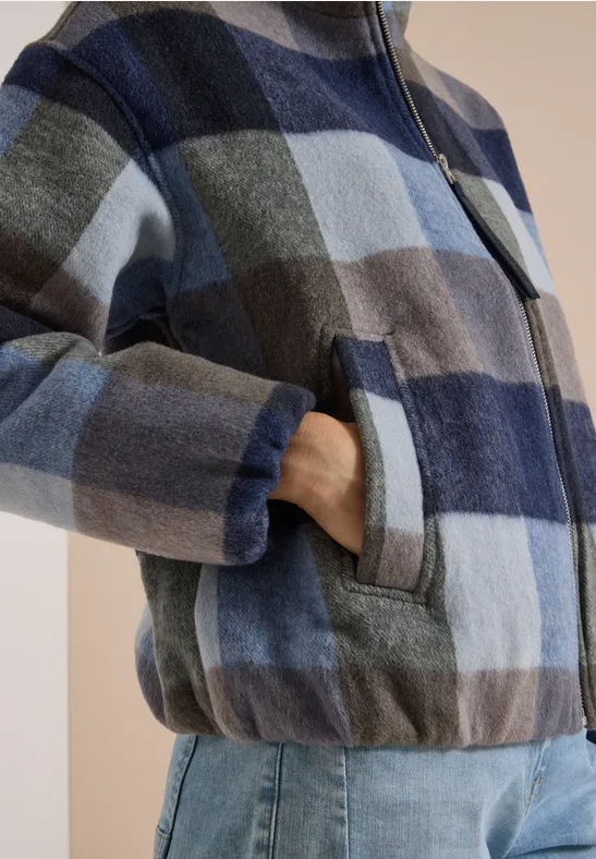 Personne porte une veste à carreaux bleus avec fermeture éclair et poches, et un jean.