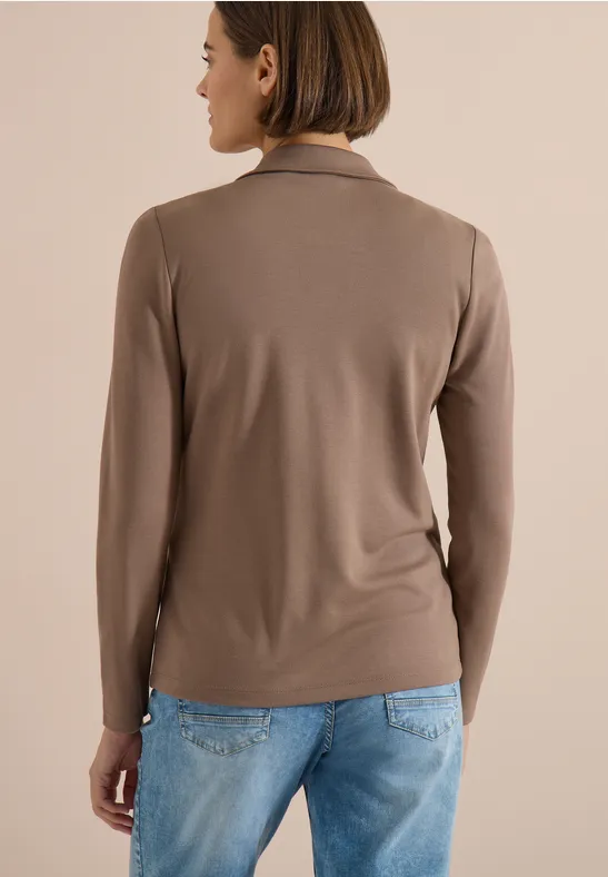 Frau von hinten mit kurzem Bob, trägt taupefarbenes Shirt und hellblaue Jeans.