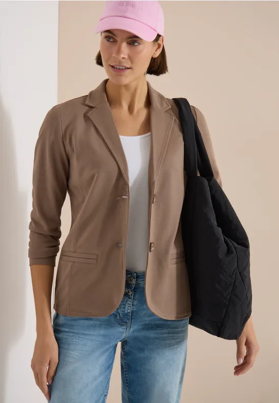 Model mit beigem Blazer, weißem Top, Jeans und schwarzer Stepp-Shopper-Tasche