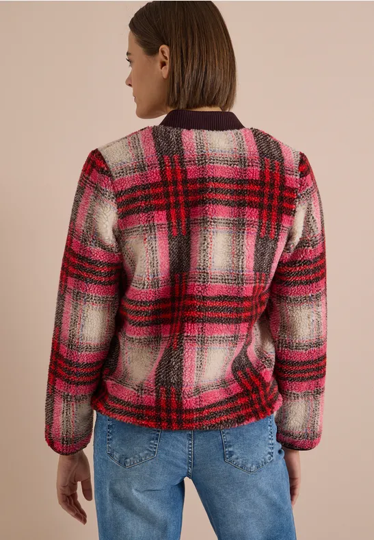 Person von hinten in einer rot-pinken karierten Jacke und blauen Jeans.