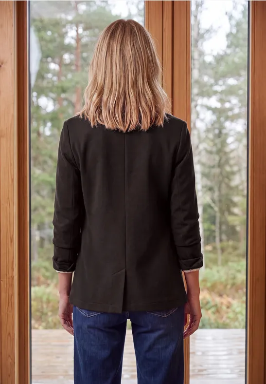 Eine Person blickt von innen durch große Fenster nach draußen in einen Wald.