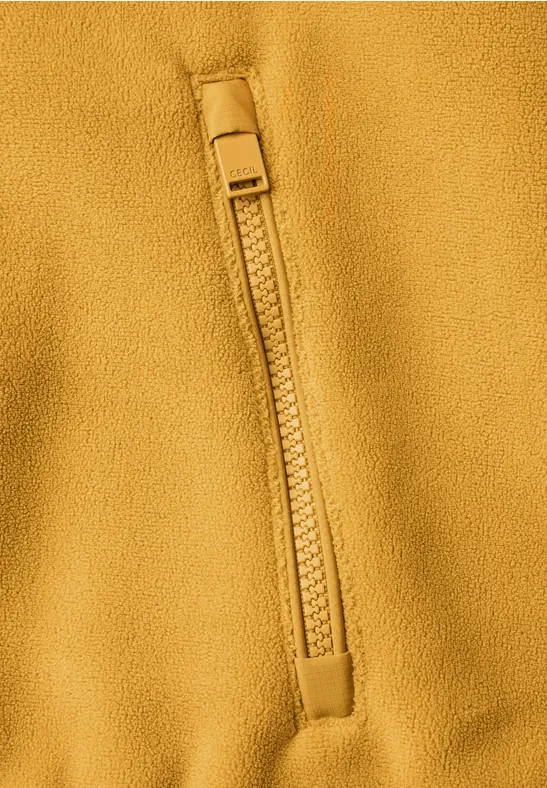 Nahaufnahme einer senfgelben Fleecejacke mit Reißverschlusstasche.