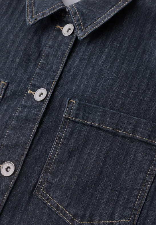 Nahaufnahme eines dunkelblauen Jeanshemds mit feinen Streifen, silbernen Knöpfen und aufgesetzter Brusttasche.