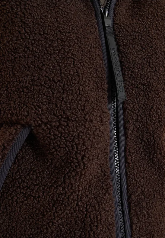 Close-up van een bruine teddyfleece jas met rits en zak.