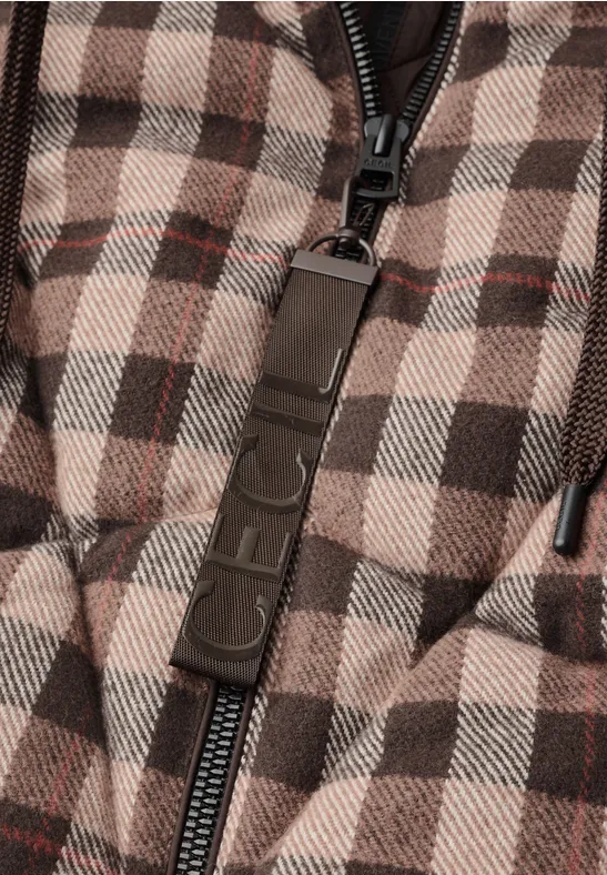 Nahaufnahme einer karierten, wattierten Jacke mit Reißverschluss und Markenanhänger.