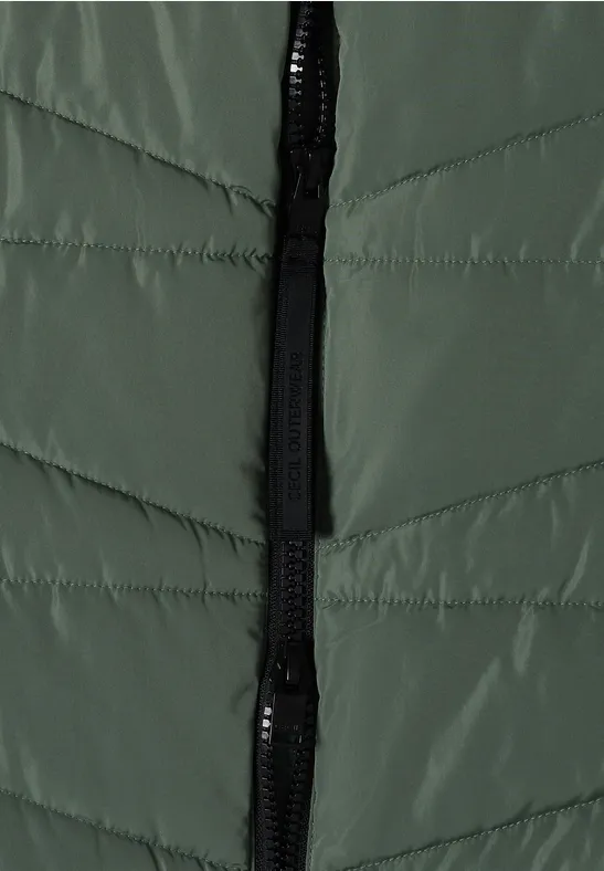 Gros plan sur une veste matelassée verte avec fermeture éclair noire.