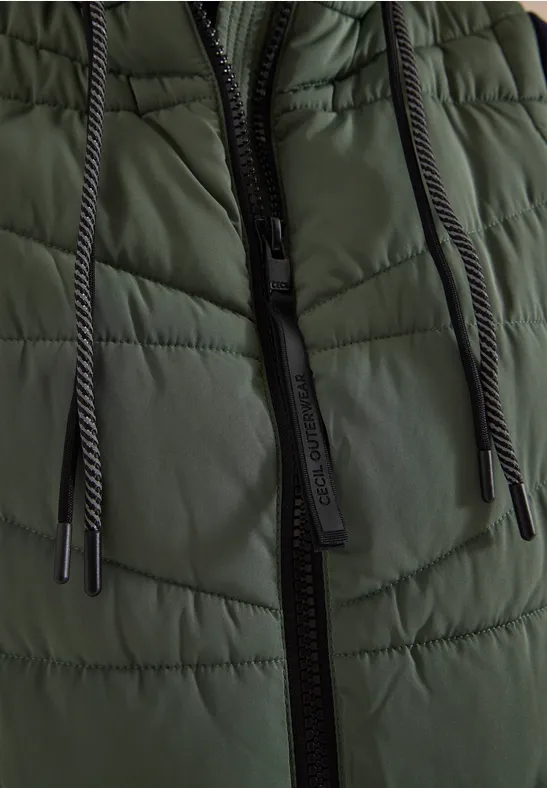 Gros plan d'une veste matelassée verte foncée avec fermeture éclair noire et cordons.