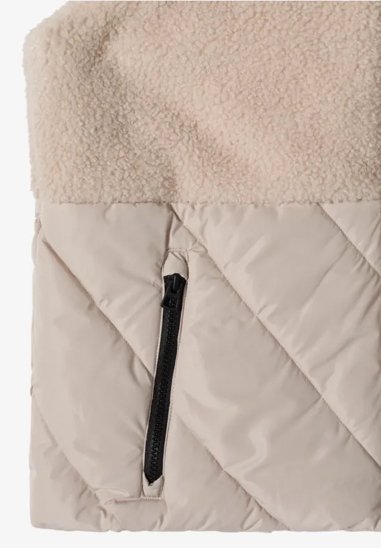 Veste beige avec surface en polaire, partie inférieure matelassée et poche zippée noire.