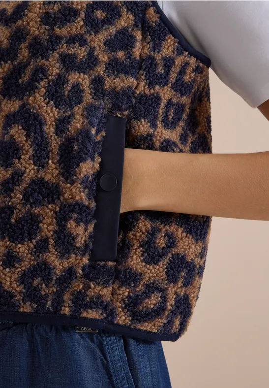 Flauschige Weste mit Leopardenmuster, Hand in Reißverschlusstasche gesteckt.