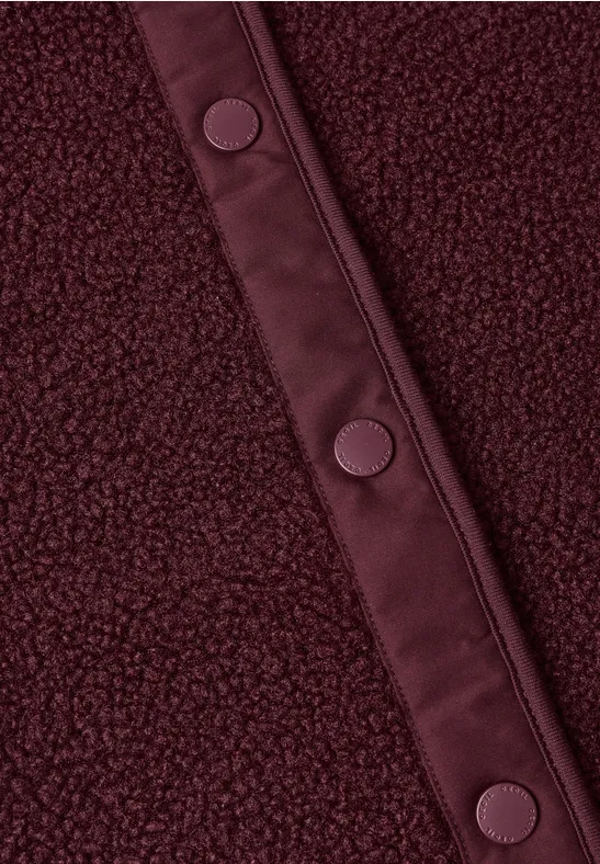 Nahaufnahme eines burgunderroten Fleece-Stoffes mit Ledereinfassung und Druckknöpfen.