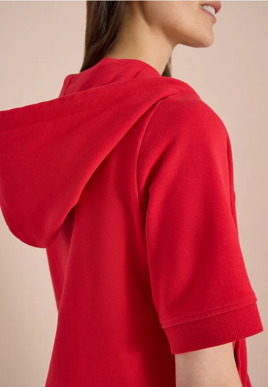 Zijaanzicht van een rode korte-mouw capuchontrui gedragen door een persoon