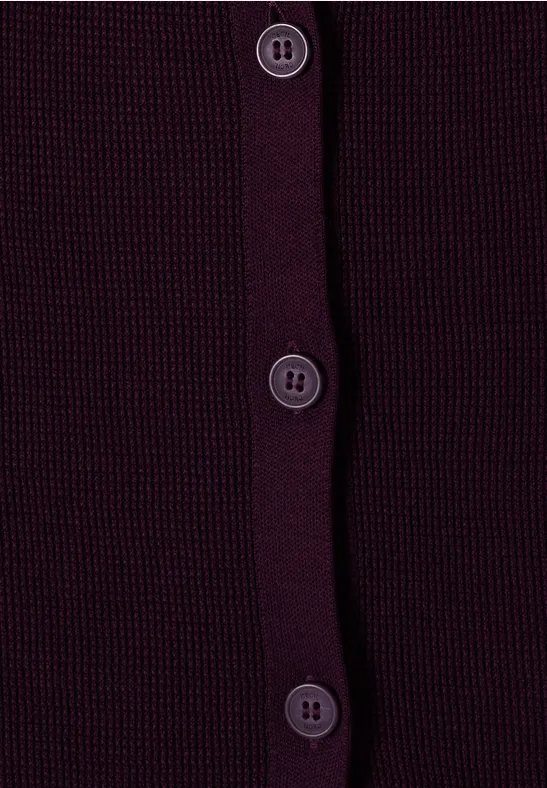 Nahaufnahme eines dunkelvioletten Strickcardigans mit vier vertikal angeordneten Knöpfen.
