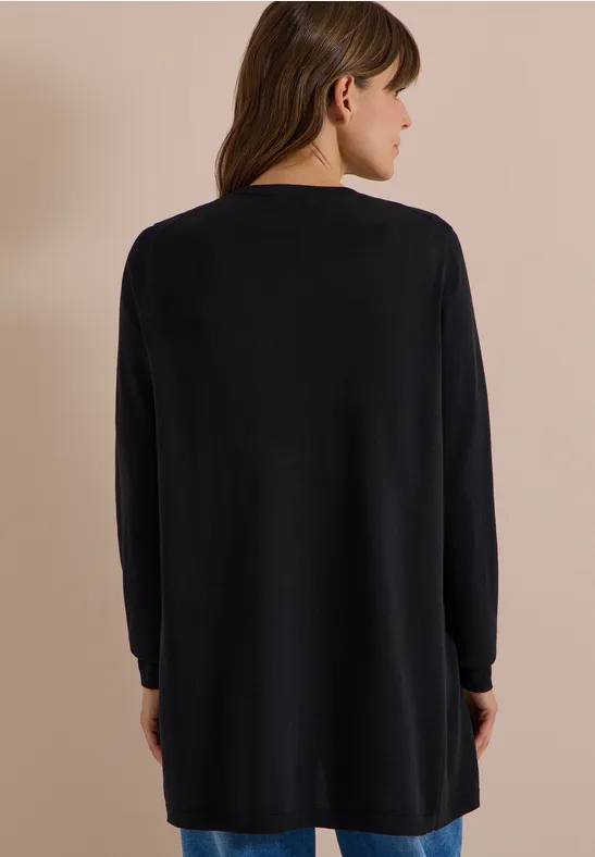 Eine Frau steht mit dem Rücken zur Kamera und trägt einen schwarzen, langen Pullover.