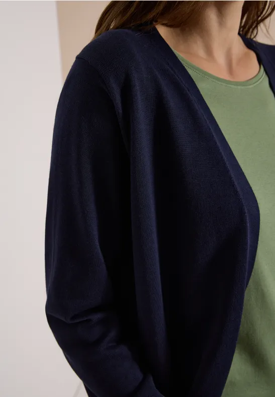 Frau in dunkelblauer Strickjacke über grünem Top
