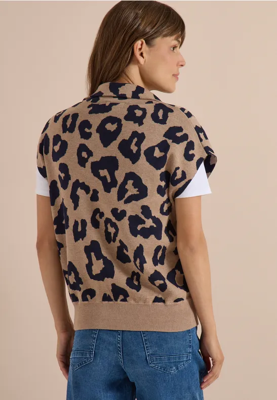 Beige Strickweste mit Leopardenmuster über weißem T-Shirt, kombiniert mit blauen Jeans.