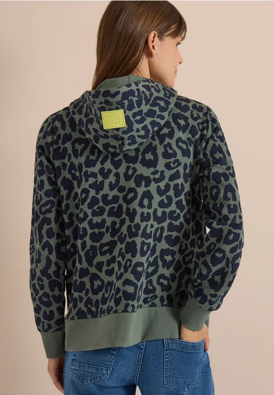 Vue de dos d'une femme portant un sweat à capuche vert à motif léopard bleu foncé.