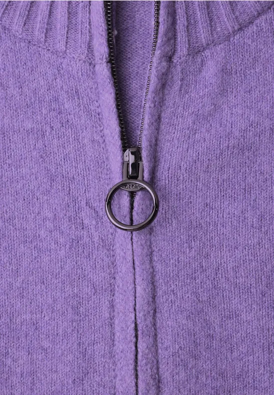 Nahaufnahme eines lila Strickpullovers mit Reißverschluss und rundem Zipperanhänger.