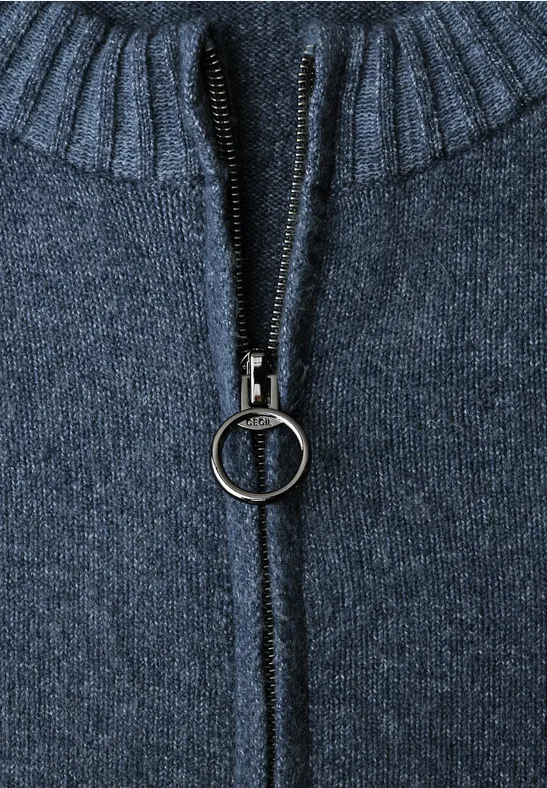 Close-up van een donkerblauwe gebreide trui met rits met ringtrekker en geribde kraag.