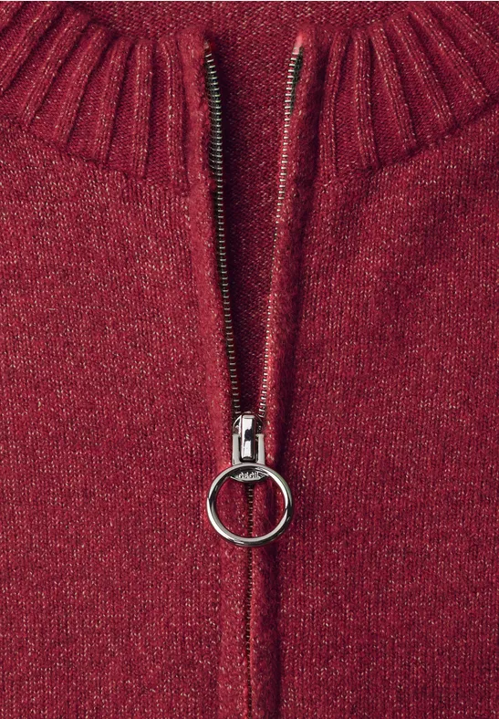 Nahaufnahme eines roten Strickpullovers mit silbernem Reißverschluss und rundem Zipper-Anhänger.