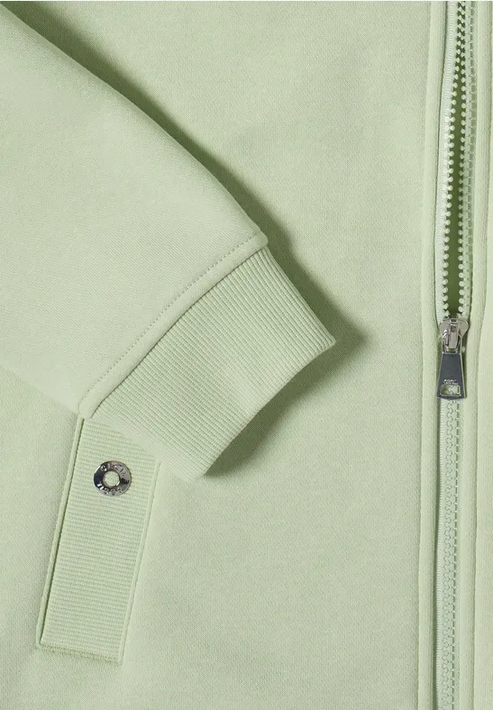 Helle pastellgrüne Jacke mit Reißverschluss, Bündchenärmel und Druckknopftasche.