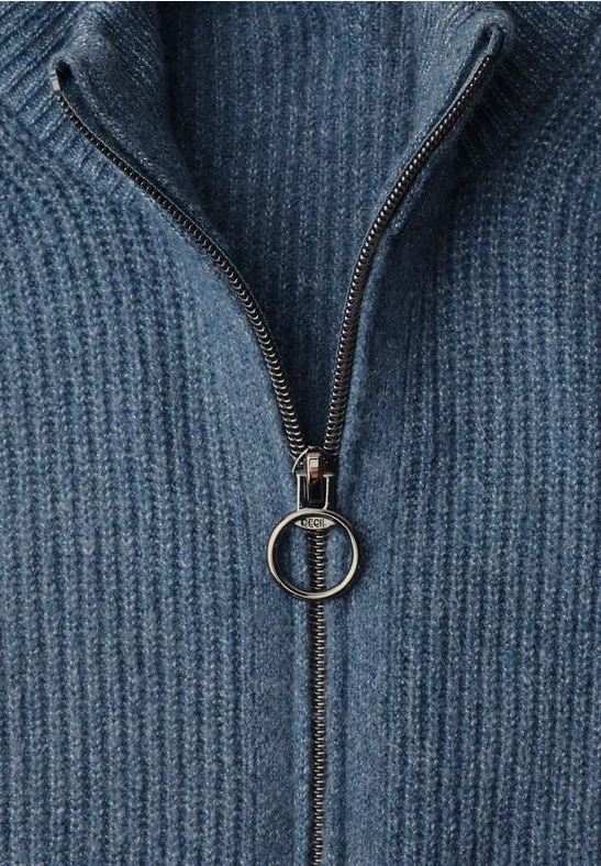 Close-up van een blauw geribbeld gebreide trui met korte ritssluiting en ringtrekker