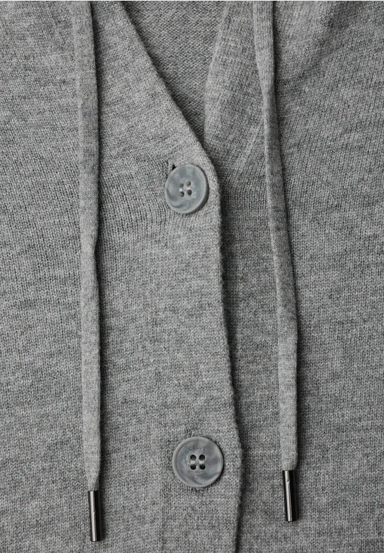Close-up van een grijze gebreide cardigan met capuchon, knopen en koordjes.
